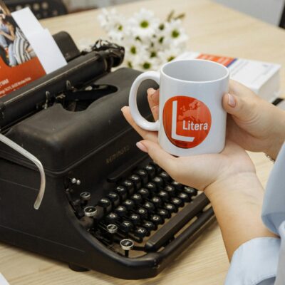 A vintage typewriter with a Litera mug held by a woman, perfect for retro themes.